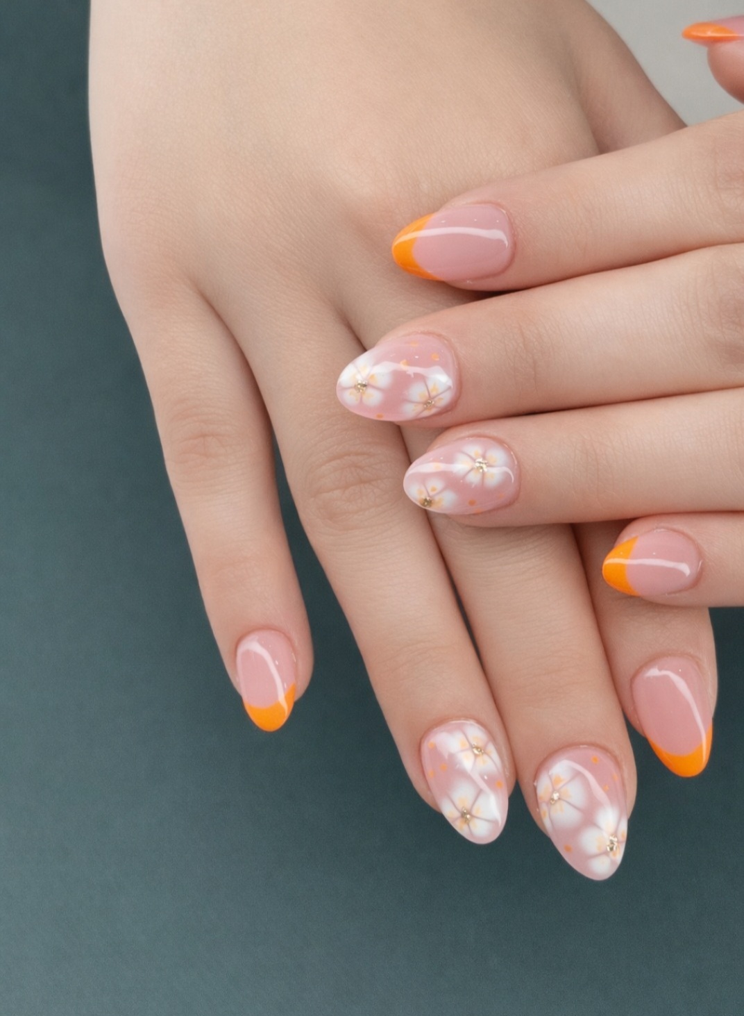 Oranje French manicure met witte bloemetjes op amandelvormige nagels